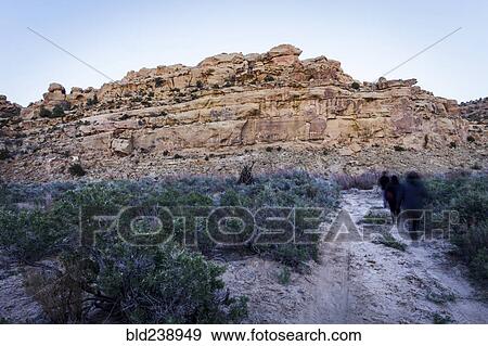 Stock Photo - People walking on trail to rock formation. Fotosearch