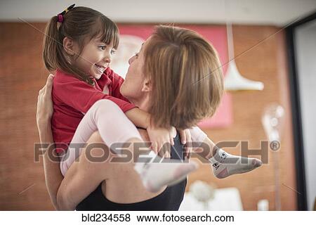Stock Photo - Playful Hispanic mother carrying daughter. Fotosearch