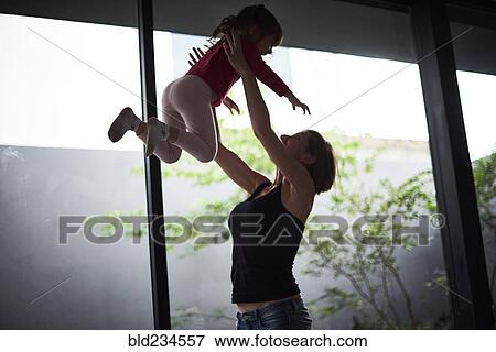 Playful Hispanic mother lifting daughter View Large Photo Image Stock Photo - Playful Hispanic mother lifting daughter. Fotosearch