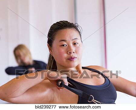 Stock Photo - Portrait of Asian woman pulling handle in gymnasium. Fotosearch