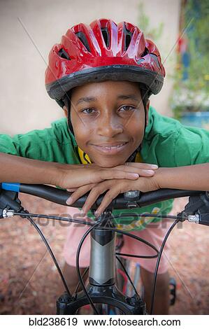 Portrait of Black boy leaning on bicycle handlebar View Large Photo Image Stock Photo - Portrait of Black boy leaning on bicycle handlebar. Fotosearch
