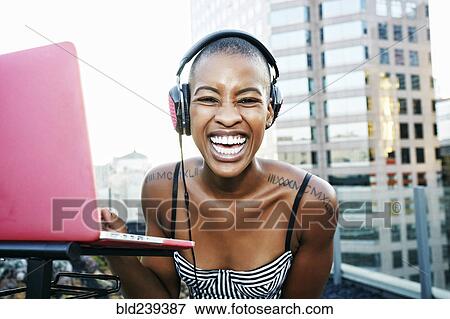 Stock Photo - Portrait of Black DJ laughing on urban rooftop. Fotosearch