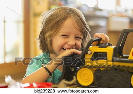 Stock Photo - Portrait of Caucasian boy playing with toy bulldozer. Fotosearch