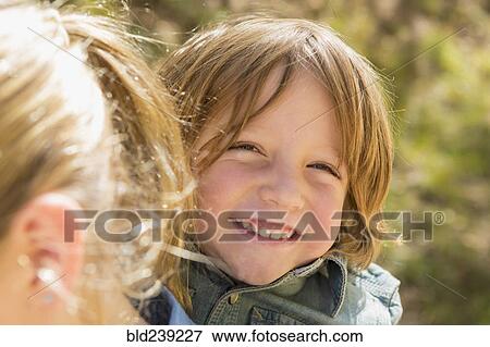 Stock Photo - Portrait of Caucasian boy smiling behind sister. Fotosearch