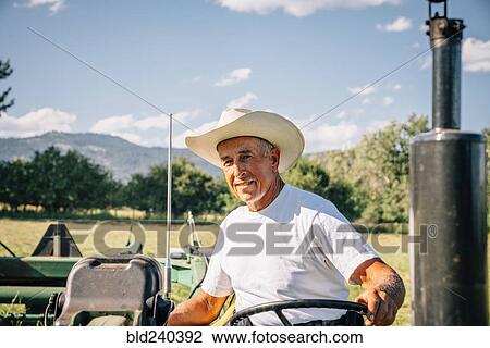 Stock Image - Portrait of Caucasian farmer on tractor. Fotosearch