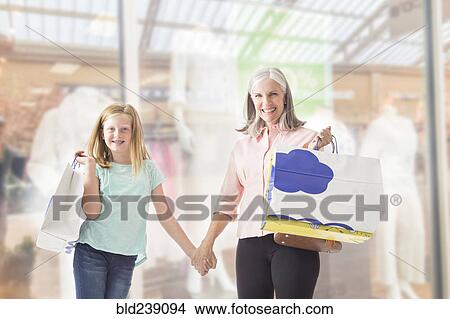 Portrait of Caucasian grandmother and granddaughter holding shopping bags View Large Photo Image Picture - Portrait of Caucasian grandmother and granddaughter holding shopping bags. Fotosearch