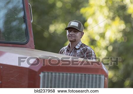 Stock Photo - Portrait of Caucasian man near tractor. Fotosearch