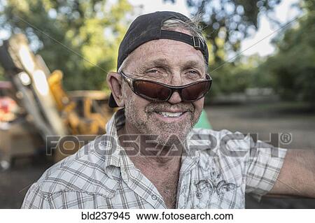 Stock Photography - Portrait of Caucasian man wearing sunglasses and baseball cap. Fotosearch
