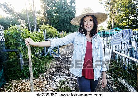 Stock Photo - Portrait of Caucasian woman leaning on shovel in garden. Fotosearch