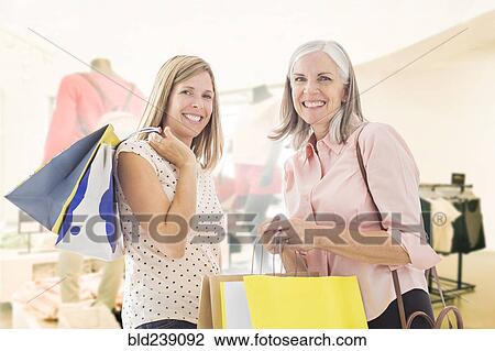 Stock Image - Portrait of Caucasian women holding shopping bags. Fotosearch