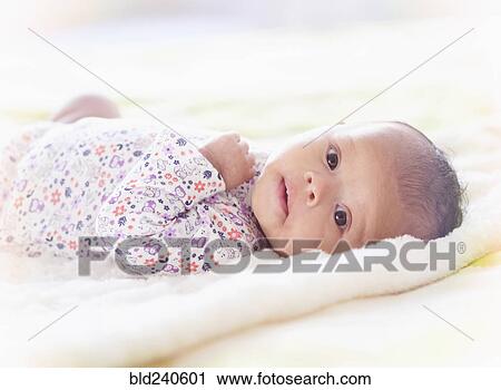 Stock Image - Portrait of Hispanic baby girl laying on blanket. Fotosearch
