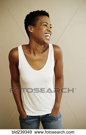 Stock Photo - Portrait of laughing Black woman with hands in pockets. Fotosearch