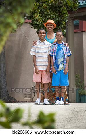 Portrait of mother and twin sons standing behind foliage View Large Photo Image Stock Photography - Portrait of mother and twin sons standing behind foliage. Fotosearch