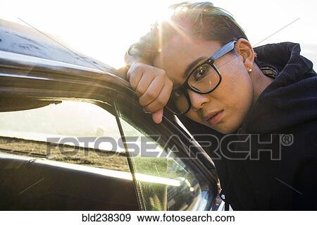 Portrait of serious androgynous Asian woman leaning on car View Large Photo Image Stock Photo - Portrait of serious androgynous Asian woman leaning on car. Fotosearch