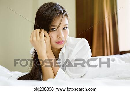 Portrait of serious Asian teenage girl laying on bed View Large Photo Image Stock Photo - Portrait of serious Asian teenage girl laying on bed. Fotosearch