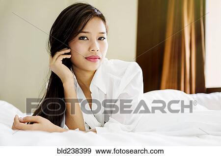 Stock Photo - Portrait of serious Asian teenage girl laying on bed. Fotosearch