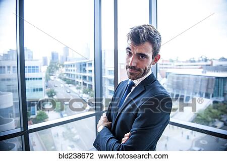 Stock Image - Portrait of serious Hispanic businessman posing near window. Fotosearch