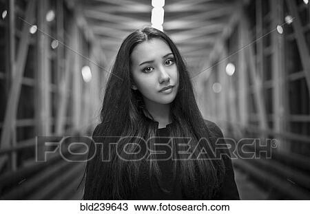 Stock Image - Portrait of serious Mixed Race teenage girl on footbridge. Fotosearch