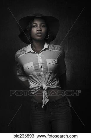 Stock Image - Portrait of serious mixed race woman wearing hat. Fotosearch