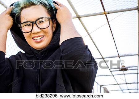 Stock Photograph - Portrait of smiling androgynous Asian woman wearing hoodie. Fotosearch