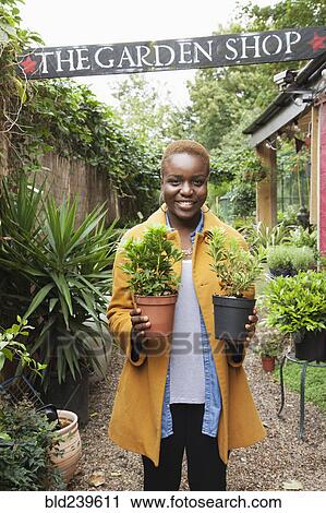 Portrait of smiling Black woman holding potted plants View Large Photo Image Stock Image - Portrait of smiling Black woman holding potted plants. Fotosearch