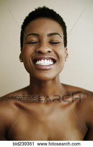 Stock Image - Portrait of smiling Black woman with eyes closed. Fotosearch
