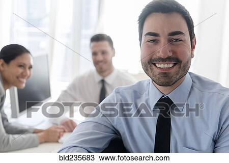 Stock Image - Portrait of smiling businessman in office. Fotosearch