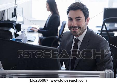 Stock Photo - Portrait of smiling businessman using computer in office. Fotosearch