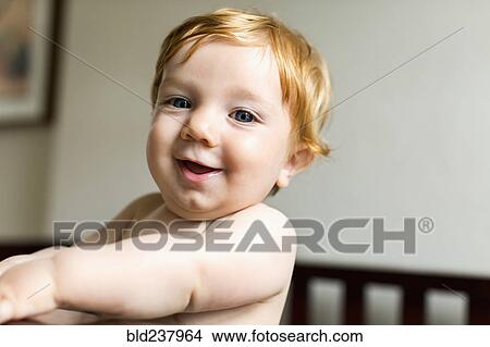 Picture - Portrait of smiling Caucasian baby boy standing in crib. Fotosearch