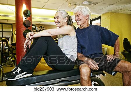 Stock Image - Portrait of smiling Caucasian couple in gymnasium. Fotosearch