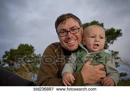 Stock Photo - Portrait of smiling Caucasian father holding baby son. Fotosearch