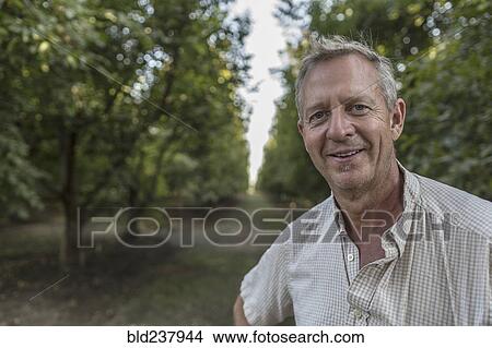 Portrait of smiling Caucasian man in orchard View Large Photo Image Picture - Portrait of smiling Caucasian man in orchard. Fotosearch