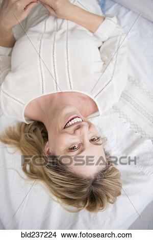 Portrait of smiling Caucasian woman laying on bed View Large Photo Image Picture - Portrait of smiling Caucasian woman laying on bed. Fotosearch