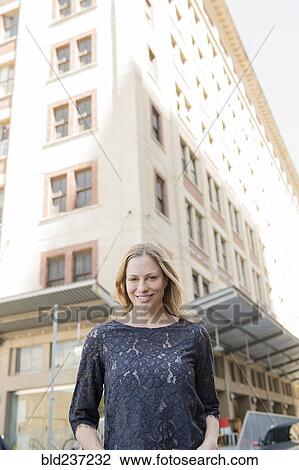 Stock Image - Portrait of smiling Caucasian woman standing in city. Fotosearch