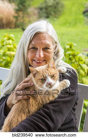Stock Image - Portrait of smiling Caucasian woman holding cat. Fotosearch