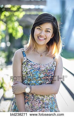 Stock Image - Portrait of smiling Chinese woman wearing dress. Fotosearch