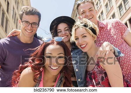 Stock Image - Portrait of smiling friends posing in city. Fotosearch