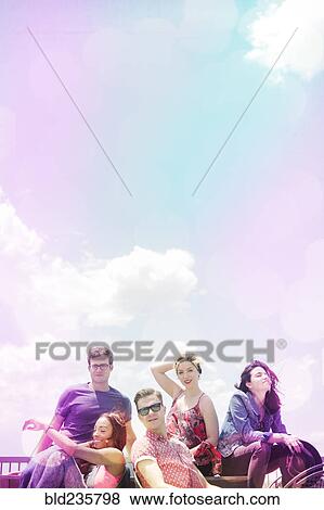 Stock Photo - Portrait of smiling friends under sunny sky. Fotosearch