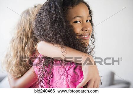 Portrait of smiling girl hugging friend View Large Photo Image Stock Photograph - Portrait of smiling girl hugging friend. Fotosearch