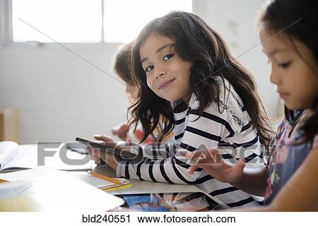Portrait of smiling girl using digital tablet in classroom View Large Photo Image Stock Image - Portrait of smiling girl using digital tablet in classroom. Fotosearch