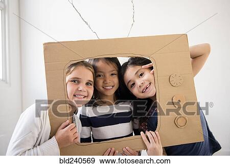 Portrait of smiling girls holding cardboard television View Large Photo Image Stock Photo - Portrait of smiling girls holding cardboard television. Fotosearch
