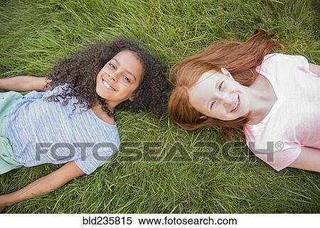 Portrait of smiling girls laying in grass View Large Photo Image Stock Photography - Portrait of smiling girls laying in grass. Fotosearch