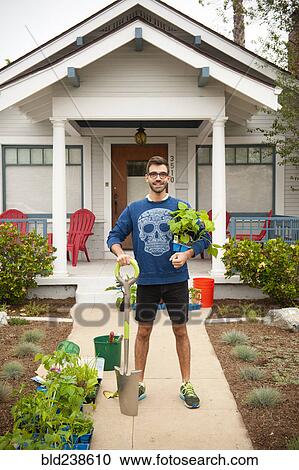 Portrait of smiling Hispanic man holding shovel and plants near house View Large Photo Image Stock Image - Portrait of smiling Hispanic man holding shovel and plants near house. Fotosearch