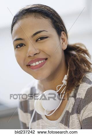 Portrait of smiling Hispanic woman wearing headphones around neck View Large Photo Image Stock Image - Portrait of smiling Hispanic woman wearing headphones around neck. Fotosearch