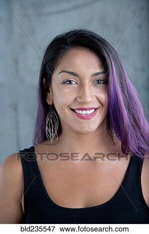 Stock Photo - Portrait of smiling Hispanic woman with purple hair. Fotosearch