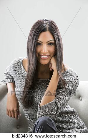 Portrait of smiling Indian woman sitting on sofa View Large Photo Image Stock Photograph - Portrait of smiling Indian woman sitting on sofa. Fotosearch