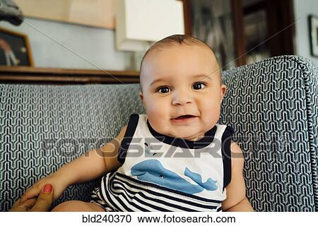 Stock Image - Portrait of smiling Mixed Race baby boy on chair. Fotosearch