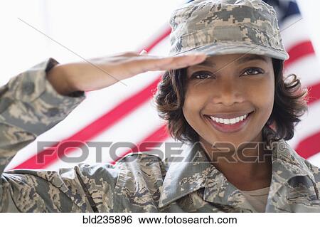 Stock Photograph - Portrait of smiling Mixed Race soldier saluting near American flag. Fotosearch
