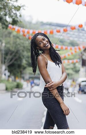 Stock Photo - Portrait of smiling Mixed Race woman standing in street. Fotosearch
