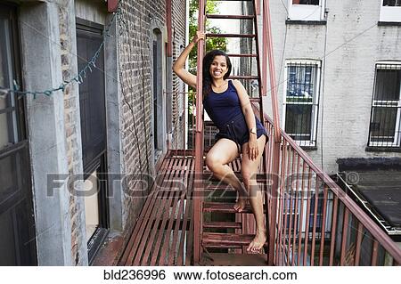 Portrait of smiling woman sitting on urban fire escape View Large Photo Image Stock Photograph - Portrait of smiling woman sitting on urban fire escape. Fotosearch